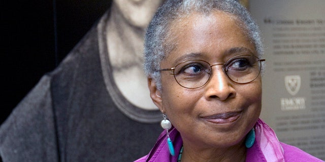 FILE - In this April 23, 2009 file photo, Alice Walker stands in front of a picture of herself from 1974 as she tours her archives at Emory University, in Atlanta. (AP Photo/John Amis, File)