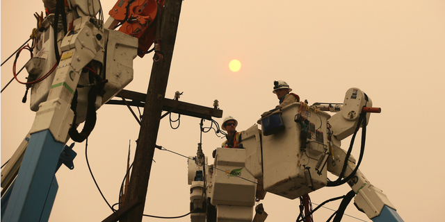 FILE - In this Nov. 9, 2018 file photo, Pacific Gas & Electric crews work to restore power lines in Paradise, Calif. The Northern California utility on Monday, Dec. 17, said it terminated one of its contractors helping with wildfire recovery after three workers posted on social media insensitive photos and comments poking fun at victims and the region. (AP Photo/Rich Pedroncelli, File)