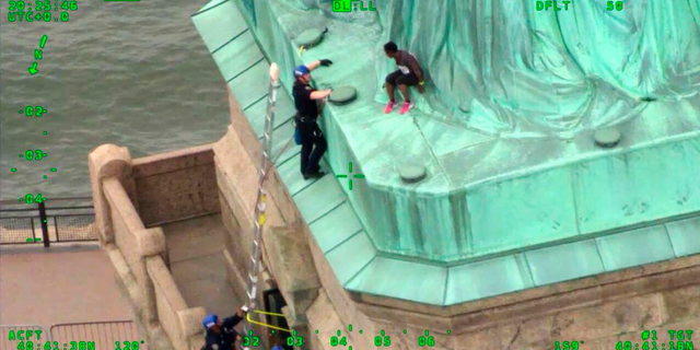 FILE - In this July 4, 2018, file photo from video provided by the New York City Police Department, members of the NYPD Emergency Service Unit work to safely remove Therese Okoumou, who climbed onto the Statue of Liberty to protest the border separation of children. Okoumou was convicted of misdemeanor charges on Monday, Jan. 17, 2018. The charges include trespassing and carry a potential penalty of up to 18 months in prison. (NYPD via AP, File)
