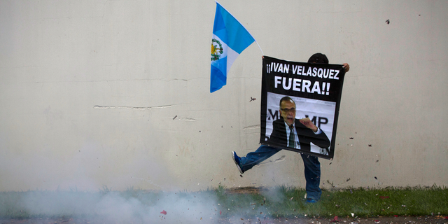 FILE - In this Aug. 31, 2018 file photo, firecrackers go off as a supporter in favor of a decision by Guatemala's President Jimmy Morales to shut down a U.N.-sponsored anti-graft commission led by Ivan Velasquez, protests outside the United Nations International Commission Against Impunity, CICIG, headquarters in Guatemala City. The Foreign Ministry said on Tuesday, Dec. 18, 2018, that the country withdrew diplomatic immunity from 11 workers with the U.N.-sponsored anti-graft commission who have investigated cases of alleged corruption, including ones targeting President Jimmy Morales’ son and brother. (AP Photo/Moises Castillo, File)