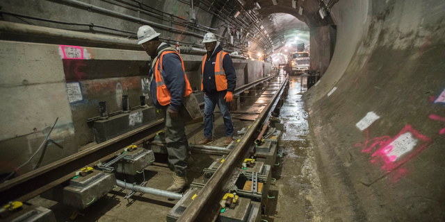 In this Nov. 29, 2018 photo, a construction crew works on the tracks of the East Side Access project beneath Grand Central Terminal in New York. The super-pricey railroad hub is taking shape, dogged by billion-dollar cost overruns and a decade of delays, but still impressive as an engineering marvel. (AP Photo/Mary Altaffer)