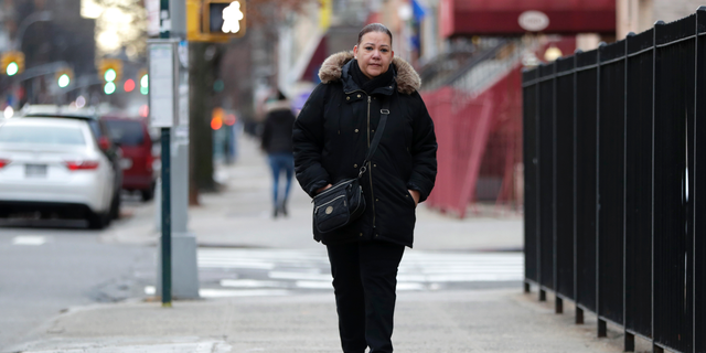 In a photo taken Dec. 23, 2018, Flavia Cabral walks to her mother's home in the Bronx section of New York. Cabral, who works two jobs, will be among many people benefiting from the minimum wage raise which will hit $15 on Dec. 31st. (AP Photo/Julio Cortez)