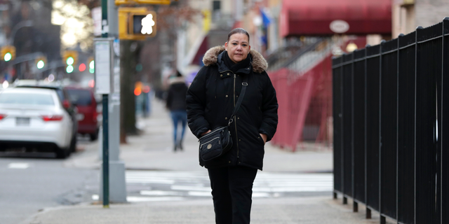 In a photo taken Dec. 23, 2018, Flavia Cabral walks to her mother's home in the Bronx section of New York. Cabral, who works two jobs, will be among many people benefiting from the minimum wage raise which will hit $15 on Dec. 31st. (AP Photo/Julio Cortez)