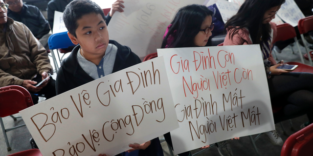 Bill Nguyen, 12, and Jade Nguyen, 9, hold signs at a rally protesting President Donald Trump's deportation policy to deport Vietnamese refugees, at the Mary Queen of Vietnam Church in New Orleans, Thursday, Dec. 20, 2018. (AP Photo/Gerald Herbert)