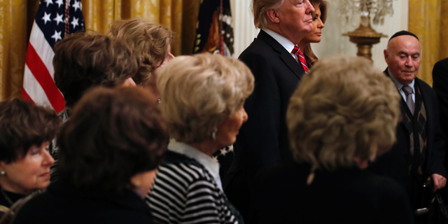 President Donald Trump and first lady Melania Trump are joined by Holocaust survivors, as they attend a Hanukkah reception, Thursday, Dec. 6, 2018, in the East Room of the White House in Washington.
