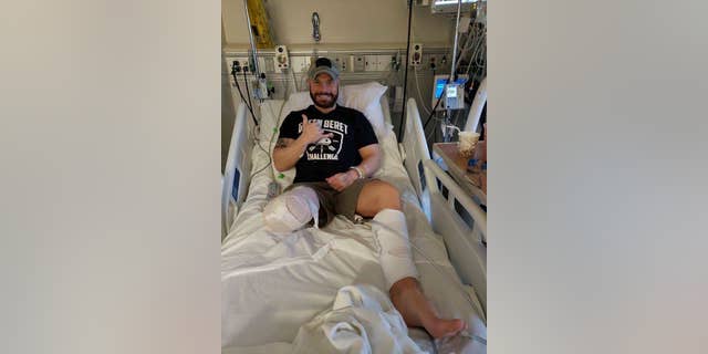 This photo provided by Earl Granville,  Alex Douglass gives a thumbs up after his surgery at the Hospital of Special Surgery in Manhattan on Dec. 12, 2018 in New York.  The Pennsylvania state police trooper who was shot in a 2014 ambush has had his right leg amputated below the knee. (Earl Granville via AP)