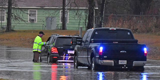 An East Baton Rouge Parish Sheriff's deputy speaks with a stranded motorist on Groom Road near Leland Avenue before pulling the woman to safety, Thursday, Dec. 27, 2018, as severe weather impacts the area in Baker, La. (Hilary Scheinuk/The Advocate via AP)