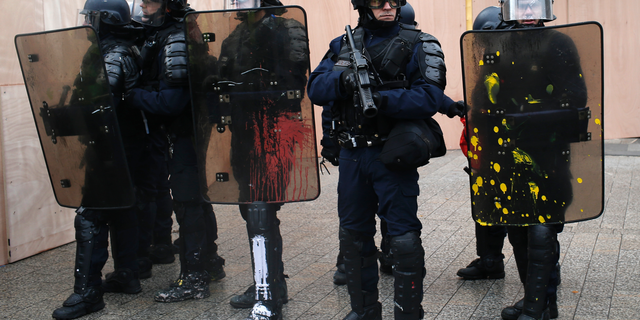 FILE - In this Saturday, Dec. 8, 2018 file photo, riot police officers stand guard on the Champs-Elysees avenue in Paris. A French police labor union is urging the government to invest in rebuilding the country’s police forces while calling for a work slowdown to protest planned cuts in the national police budget. The Alliance union said on Monday, Dec. 17 that French lawmakers are set to vote on 62 million euros ($70 million) in budget cuts this week that “will once again result in downgraded work conditions,” if approved. (AP Photo/Rafael Yaghobzadeh, file)
