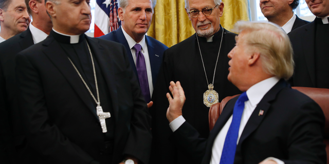 President Donald Trump turns to House Majority Leader Kevin McCarthy, R-Calif., during an event to sign H.R. 390, the "Iraq and Syria Genocide Relief and Accountability Act of 2018," in the Oval Office of the White House, Tuesday, Dec. 11, 2018, in Washington. (AP Photo/Jacquelyn Martin)