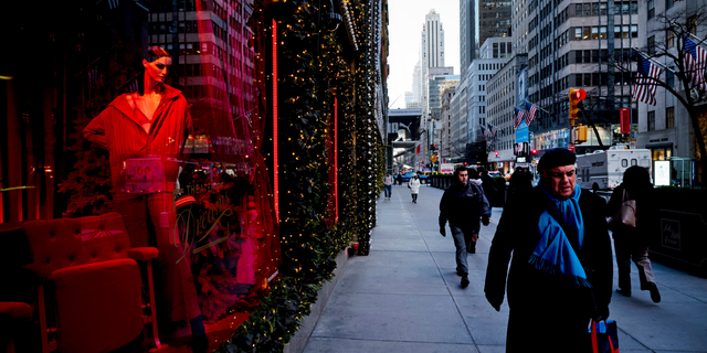 FILE - In this Wednesday, Dec. 5, 2018 file photo, people walk past a holiday window at Saks Fifth Avenue, in New York. U.S. consumer confidence tumbled this month as Americans began to worry that economic growth will moderate next year. The Conference Board, a business research group, says its consumer confidence index fell to 128.1 in December, down from 136.4 in November and lowest since July. (AP Photo/Mark Lennihan, File)