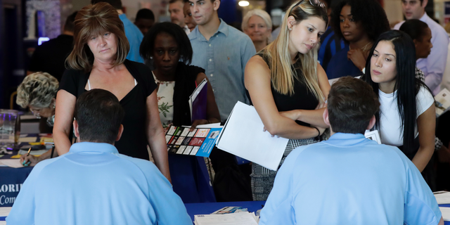 FILE- In this June 21, 2018 file photo, job applicants talks with representatives from Aldi at a job fair hosted by Job News South Florida, in Sunrise, Fla. On Thursday, Dec. 6, payroll processor ADP reports how many jobs private employers added in November. (AP Photo/Lynne Sladky, File)