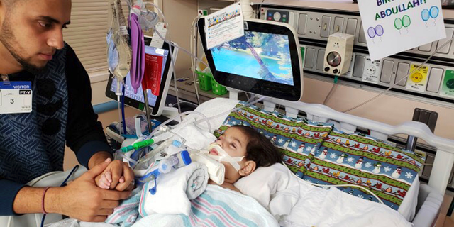 This recent but undated photo, released Monday, Dec. 17, 2018 by the Council on American-Islamic Relations in Sacramento, Calif., shows Ali Hassan with his dying 2-year-old son Abdullah in a Sacramento hospital. (Council on American-Islamic Relations via AP)