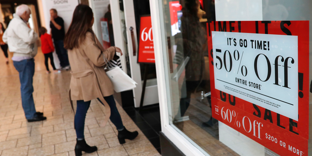 FILE - In this Dec. 24, 2018, file photo, discount placards stand in the window of a clothing store as last-minute shoppers finish up their Christmas gift lists at the Cherry Creek Mall in Denver. Americans buoyed by a strong economy pushed holiday sales growth to a six-year high. (AP Photo/David Zalubowski, File)