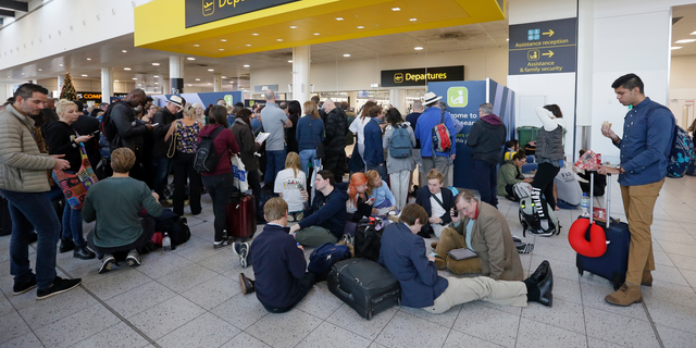 People wait outside the departures gate at Gatwick airport, near London, as the airport remains closed with incoming flights delayed or diverted to other airports, after drones were spotted over the airfield last night and this morning, Thursday, Dec. 20, 2018. London's Gatwick Airport remained shut during the busy holiday period Thursday while police and airport officials investigate reports that drones were flying in the area of the airfield.