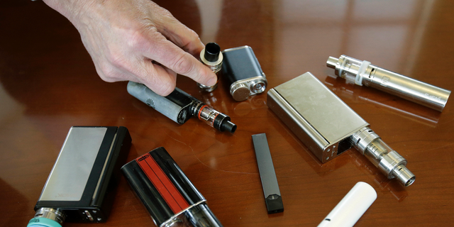 In this April 10, 2018, file photo, a high school principal displays vaping devices that were confiscated from students in such places as restrooms or hallways at the school in Massachusetts. 