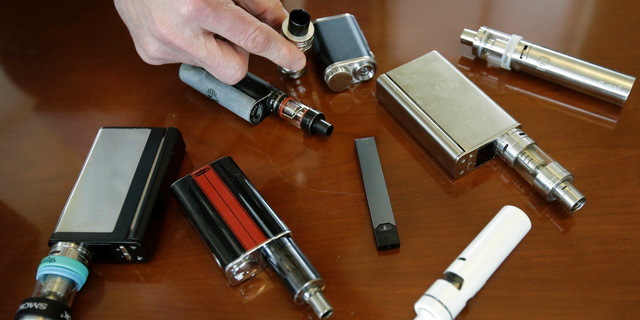 In this April 10, 2018, file photo, a high school principal displays vaping devices that were confiscated from students in such places as restrooms or hallways at the school in Massachusetts.
