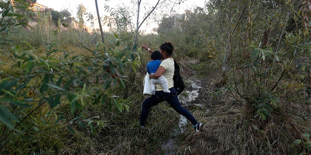 Yesenia Martinez, 24, carrying her eight-month-old son Daniel as she looked for a place to cross the U.S. border wall. (AP Photo/Rebecca Blackwell)