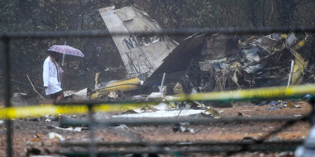 A person investigates the scene of a small plane crash in a city park which killed all on board, Thursday, Dec. 20, 2018, in northwest Atlanta.