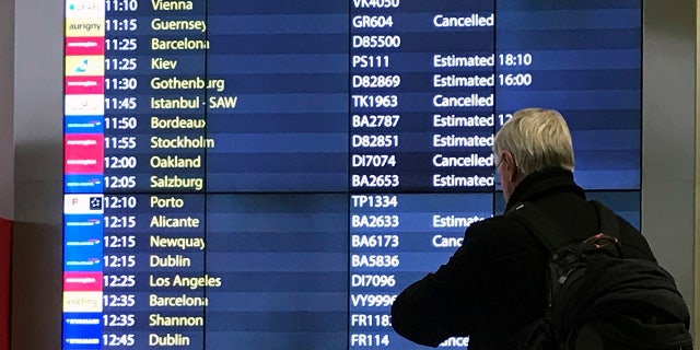 A passenger checks an arrivals board at Gatwick Airport in England, Friday, Dec. 21, 2018. (AP Photo/Kirsty Wigglesworth)