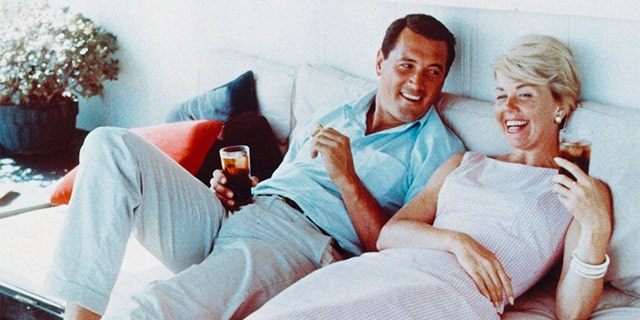 Rock Hudson (1925-1985) and Doris Day laughing and holding drinks, circa 1960. — Getty