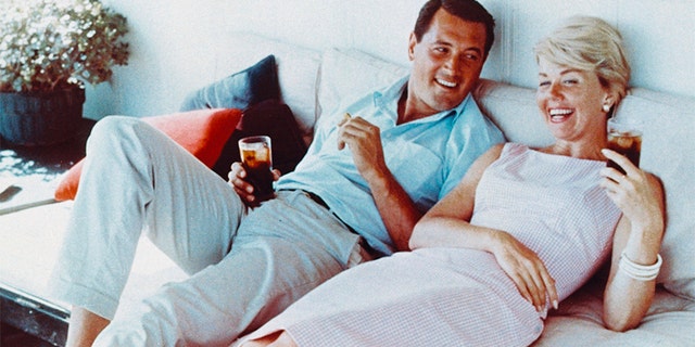 Rock Hudson (1925-1985) and Doris Day laughing and holding drinks, circa 1960. — Getty