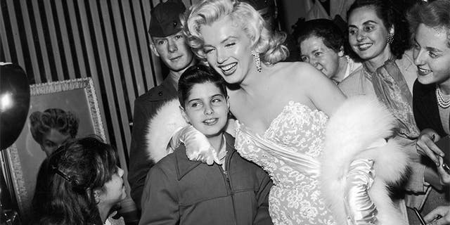 Marilyn Monroe is all smiles as she poses with fans in front of the Wilshire Beauty Shop at the premiere of director Jean Negulesco's film "How to Marry a Millionaire" in 1953.