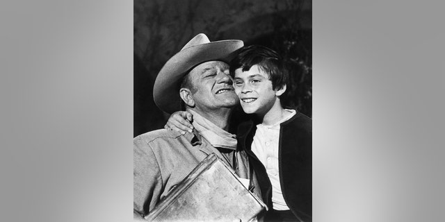 Ethan Wayne, 8, gets a hug from dad, John Wayne, after filming a shootout scene with outlaws in 'The Million Dollar Kidnapping.'