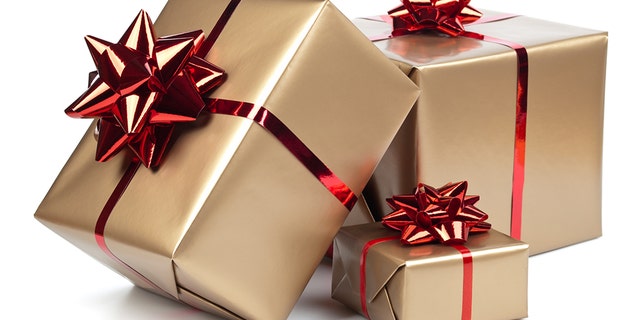 Gold gift boxes with red ribbon on white. A man in India rigged a music sound system with explosives and hid it among the wedding gifts for his former lover and her groom, who was killed. 