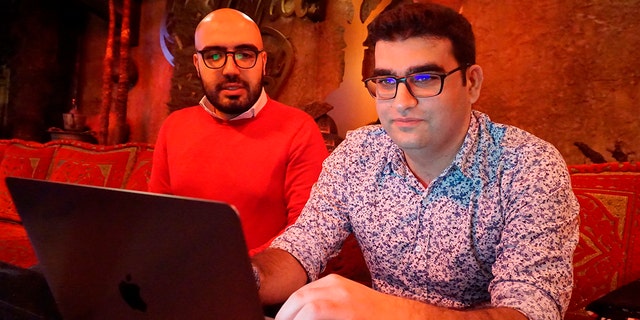 Certfa researchers Nariman Gharib, left, and Amin Sabeti look at a computer at a cafe in London on Friday, Dec. 7, 2018.