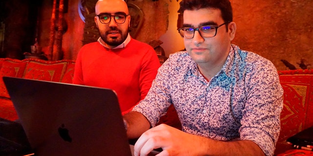 Certfa researchers Nariman Gharib, left, and Amin Sabeti look at a computer at a cafe in London on Friday, Dec. 7, 2018.