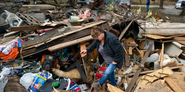 Joyce Morrissey sorting through the debris of her nephew Stephen Tirpak's house in Taylorville, Ill., Sunday. The National Weather Service said multiple tornadoes touched down in central Illinois, damaging dozens of structures and injuring multiple people. (Ted Schurter/The State Journal-Register via AP)
