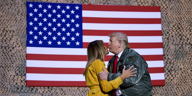 President Donald Trump kisses first lady Melania Trump during a hanger rally at Al Asad Air Base, Iraq, Wednesday, Dec. 26, 2018. 