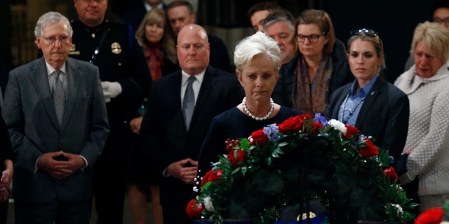 Cindy McCain, center, widow of the late Sen. John McCain, R-Ariz., views the flag-draped casket of former President George H.W. Bush as he lies in state in the Capitol Rotunda on Tuesday. At back left is Senate Majority Leader Mitch McConnell, R-Ky. (AP Photo/Patrick Semansky)