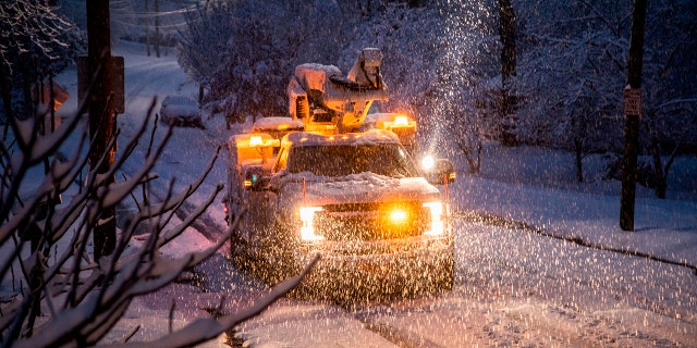 A Duke Energy crew works to restore power in Raleigh, N.C,. as snow continues to fall Sunday morning, Dec. 9, 2018.