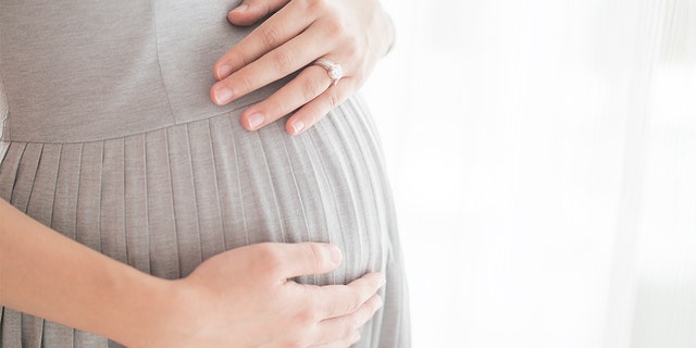 A pregnant woman holds her baby bump.