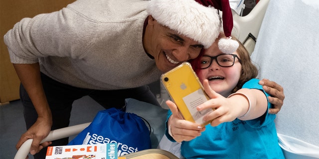 Obama bends down for a selfie with a young patient.