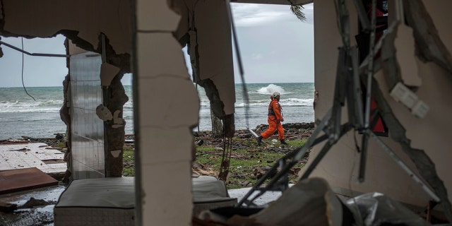 A rescuer is seen through a damaged house as he takes part in a search operation of tsunami victims in Carita, Indonesia, Sunday. (AP Photo/Fauzy Chaniago)