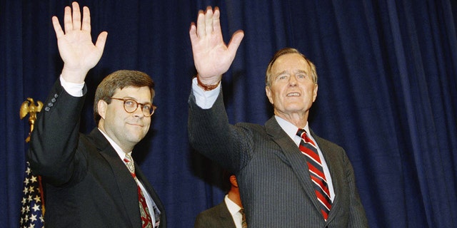 Le président George Herbert Walker Bush et le procureur général de l'époque, Bill Barr, saluent depuis une estrade.