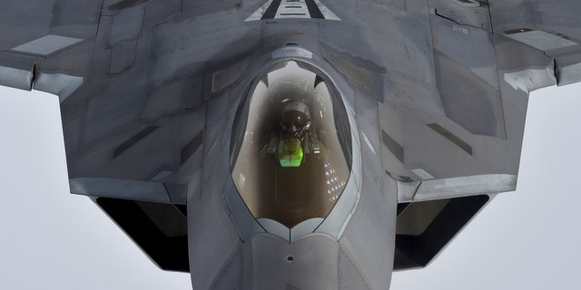 File photo - A pilot looks up from a US F-22 Raptor fighter as it prepares to refuel in mid-air with a KC-135 refueling plane over European airspace in 2016