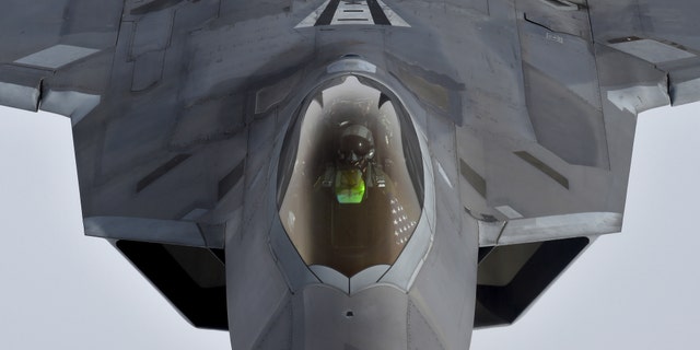 File photo - A pilot looks up from a US F-22 Raptor fighter as it prepares to refuel in mid-air with a KC-135 refueling plane over European airspace in 2016