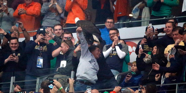 Fans cheer as "Clark," an American bald eagle, lands on the arm of a fan in the upper deck after the playing of the national anthem before the first half of the NCAA Cotton Bowl semi-final playoff football game between Clemson and Notre Dame on Saturday, Dec. 29, 2018, in Arlington, Texas.