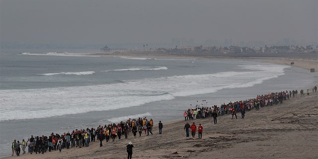 Members of various faith groups walking on the beach toward the U.S. border with Mexico. (AP Photo/Rebecca Blackwell)