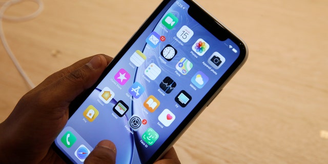 An Apple employee holds an iPhone Apple XR.