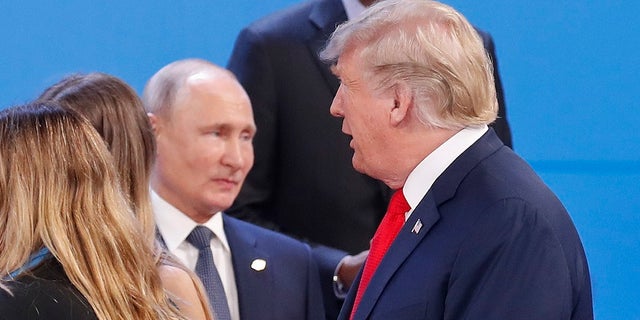 Russia's President Vladimir Putin, left, watches President Donald Trump, right, walk past him as they gather for the group photo at the start of the G20 summit in Buenos Aires, Argentina.