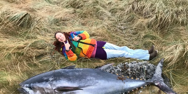 Ranger Emma Neave-Webb next to the giant Atlantic bluefin tuna found washed up on Bea Sand on Sanday, Orkney, 