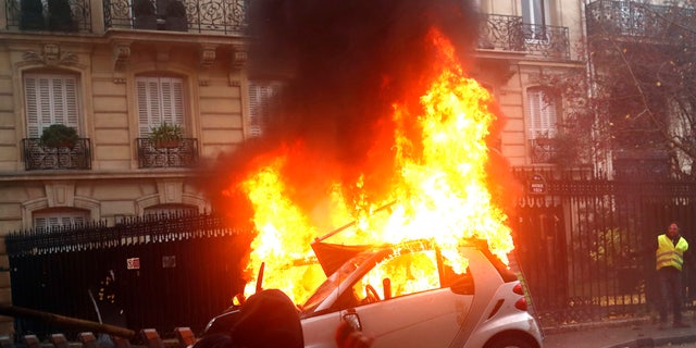 A hooded malcontent throws an object as a automobile buns during a proof Saturday, Dec.1, 2018 in Paris. Protesters indignant about rising taxes clashed with French military for a third true weekend and over 100 were arrested after pockets of demonstrators built barricades in a center of streets in executive Paris, illuminated fires and threw rocks during officers Saturday. (AP Photo/Thibault Camus)