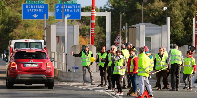 Demonstrators wearing yellow vests protest at the toll gates of a motorway, in Biarritz, southwestern France, Monday, Dec. 10, 2018.