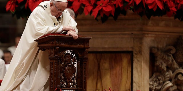 Pope Francis kneels on the altar as he celebrates the Christmas Eve Mass in St. Peter's Basilica at the Vatican.