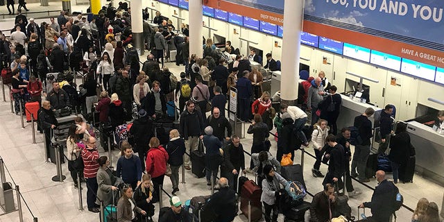 Passengers wait to check in at Gatwick Airport on Friday.