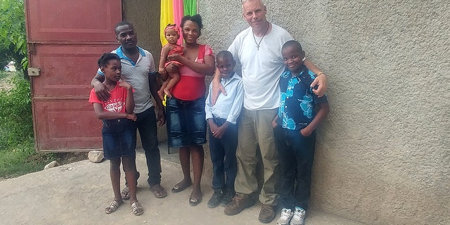 Barclay Stuart with John "Little John" Olivier's family in Haiti before the nine-year-old Haitian received the life-saving surgery.